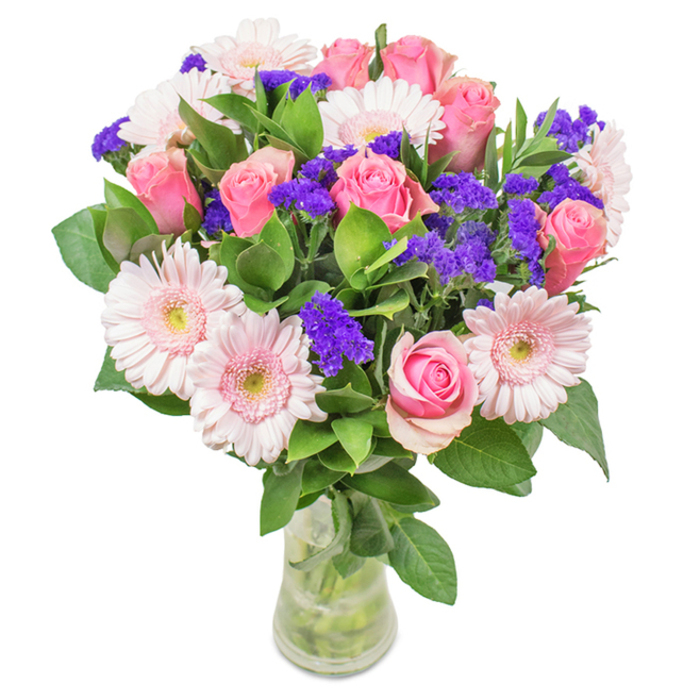 Against a crisp white backdrop, this vibrant bouquet-available for delivery across Barnet-offers a masterclass in floral artistry. Approximately seven to nine well-formed pink roses, some tightly wound and others just beginning to open, provide a focal point with their timeless spiral architecture. These are surrounded by five to seven soft pink gerbera daisies, their large, round faces and almost-whisper-white centres giving a fresh, sunlit feel reminiscent of spring walks through King George's Fields. Splashes of deep purple statice or limonium lend textural contrast and visual intrigue, elevating the soft pinks with a lively heartbeat. The ensemble is anchored by lush, deep green foliage, echoing the old-growth trees lining Barnet's avenues. Stems are clearly visible in a slender, transparent vase, their freshness undeniable-a hallmark of Barnet's own flower deliveries. Thoughtfully designed for occasions from birthdays in Underhill to anniversaries or as a gracious office accent, this arrangement conveys warmth, community, and a touch of local pride. There's a spirit of joy, celebration, and quiet affection woven through every stem, ensuring the recipient feels truly valued.