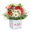 There's a vibrant sense of celebration woven through this stunning Barnet bouquet, as if a walk through Victoria Park's springtime blooms had been lovingly gathered into a single, exquisite arrangement. A profusion of ruffled peach and coral carnations, alive with gentle energy, spill softly from a pristine white gift bag. Bright white daisies with joyful yellow centres add a fresh and optimistic contrast, their crisp petals radiating calm and happiness. Wisps of delicate white baby's breath lend an ethereal lightness, while deep green, lustrous leaves collect around the base, providing a serene embrace that grounds the bouquet. Hidden among the blooms, a few unopened buds with hints of purple whisper of promise and surprises yet to unfold. The bag itself, adorned with silky ribbon handles, underscores the thoughtful presentation and is perfect for a special delivery - be it a birthday treat, a warm anniversary wish, or simply a gesture to lift someone's spirits in Barnet. Photographed against a bright, pure backdrop, this bouquet radiates expert care and sincere sentiment, promising a breath of floral freshness delivered with every petal.